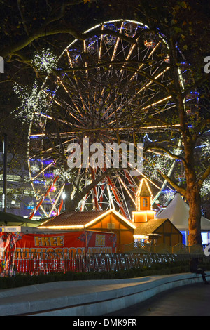 Große Riesenrad über Winterbäume auf dem Leicester Square Weihnachts-Messegelände in der Nacht Stockfoto
