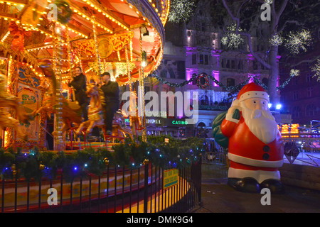 Leicester Square Weihnachtsmarkt in der Nacht große Kunststoff Vater Weihnachten neben Karussell Merry gehen rund um Kreisverkehr West End London England GB Stockfoto
