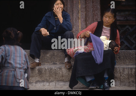 Zwei tibetische Frauen sitzen auf Treppe ruht, ist eine pflegende ihr Baby. Foto in Lhasa, Tibet, China Stockfoto