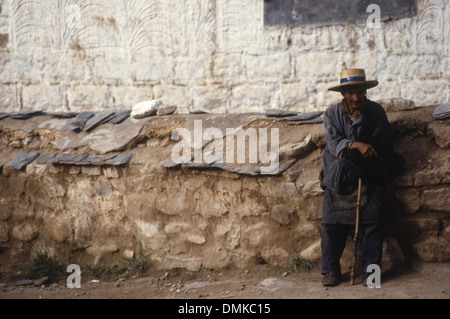 Ein armer alter Mann mit einem Gehstock stehen neben einem Gebäude in Lhasa, Tibet, China. Stockfoto