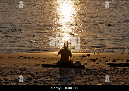 Ein junger Mann Flötenspiel am Strand in Rishikesh, Indien. Stockfoto