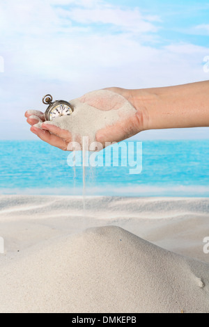 Hand mit Taschenuhr und Sand fließt am Strand Stockfoto