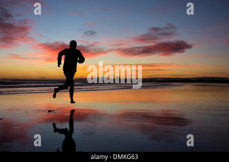 Männliche Jogger laufen barfuß am Strand bei Sonnenaufgang. Seaton Carew in der Nähe von Hartlepool, England, UK Stockfoto