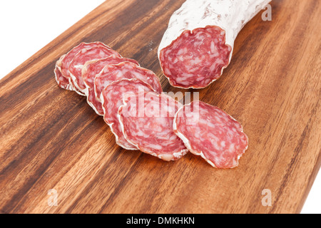 geschnittene Salami auf Holzbrett und weißem Hintergrund Stockfoto