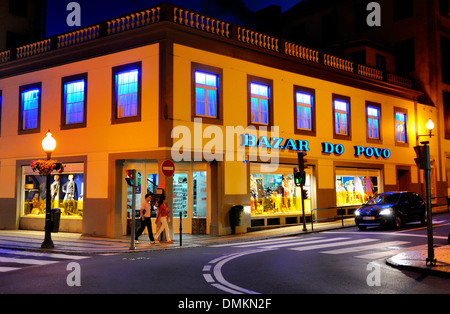 Funchal Madeira. Menschen in der Nacht zu Fuß auf einer Straße mit einem bunt beleuchteten shop Stockfoto