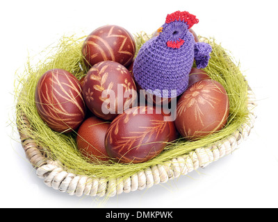 Häkeln Sitter sitzen auf Ostereier in Wicker Korb gedreht auf weiß Stockfoto