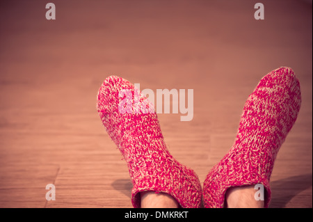 Mann Beine in roten Wollsocken männlichen gestrickte Kleidung winter handgemachte Accessoires Wohnkomfort Konzept auf hölzernen Hintergrund trendy Stockfoto