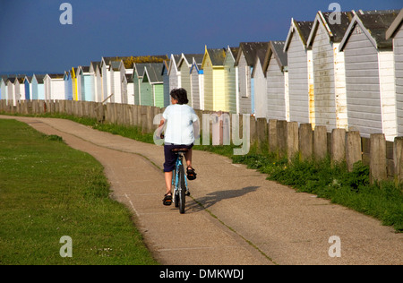 Radfahrer vorbei Strandhütten auf küstennahen Zyklus Weg (Teil der nationalen Route 2) Lancing, West Sussex, UK. Lancing Strand grün links Stockfoto