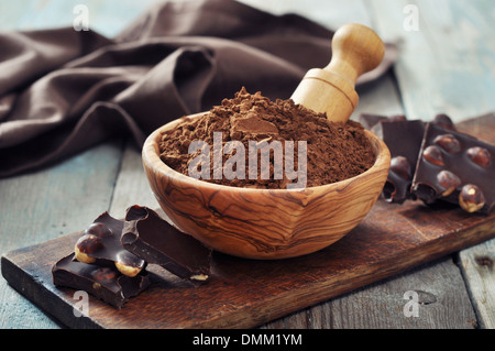 Carob Pulver in die Schüssel mit Schokostückchen auf hölzernen Hintergrund Stockfoto