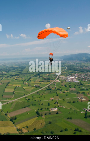 Zwei Fallschirmspringer unter einem Baldachin Tandem fliegen über eine spektakuläre Landschaft in den blauen Himmel. Stockfoto