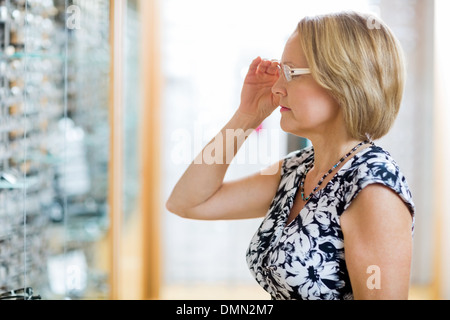 Frau versucht auf Brillen im Shop Stockfoto