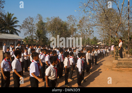 Horizontale Ansicht von Schulkindern salutieren zusammen, während ihre Fahne heben an einer Schule in Laos. Stockfoto