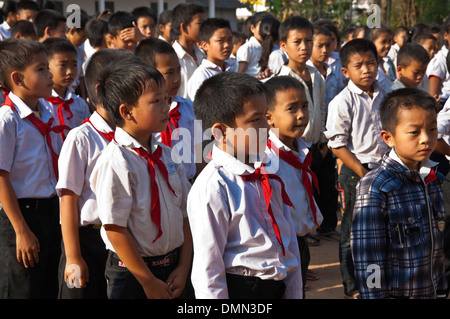 Horizontale Ansicht von Schulkindern in einer Schlange stehen, während ihre Fahne heben an einer Schule in Laos. Stockfoto