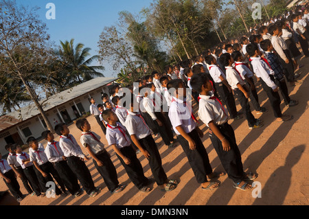 Horizontale Winkel Ansicht von Schulkindern, die ständige Aufmerksamkeit während ihrer Flagge heben an einer Schule in Laos. Stockfoto