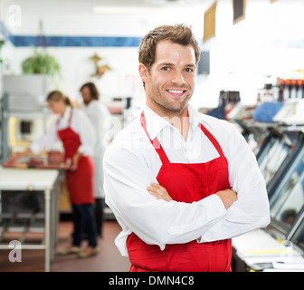 Zuversichtlich männlichen Metzger stehend Arme verschränkt im Store Stockfoto