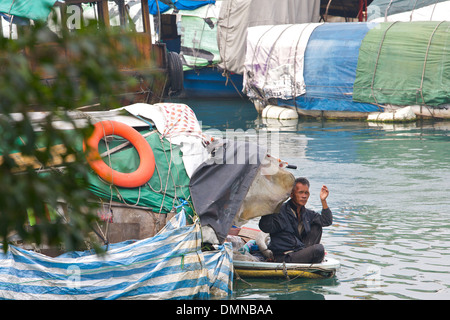 Alte chinesische Mann sitzt im Bug eines kleinen Bootes, Causeway Bay, Hong Kong. Stockfoto