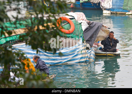 Alte chinesische Mann sitzt im Bug eines kleinen Bootes, Causeway Bay, Hong Kong. Stockfoto