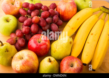 Nahaufnahme von frischen Bananen, Birnen, Äpfel und Trauben auf einem Holztisch Stockfoto