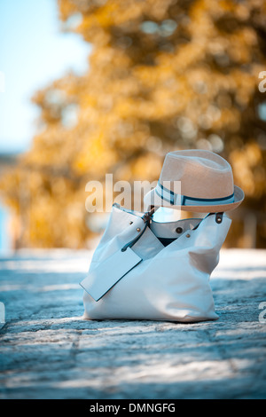 Weibliche Tasche aus Leder und Textil Hut auf Straßenpflaster am sonnigen Tag Stockfoto