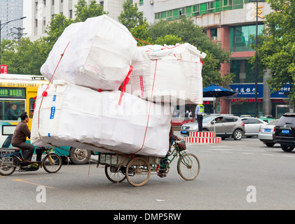 Mann auf dem Fahrrad Wagen tragen eine Last von Boxen über eine verkehrsreiche Kreuzung Xian, Provinz Shaanxi, VR China, Volksrepublik China Asien Stockfoto