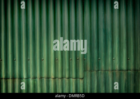 Eine grüne Wellblech-Wand mit einer Naht und Schrauben, die die gesamte Länge des Bildes Stockfoto