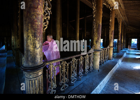 Eine Nonne ordnet ihre Gewänder nach einem Gebet an Shwenandaw Kyaung (Teak-Kloster), Mandalay, Birma. Stockfoto