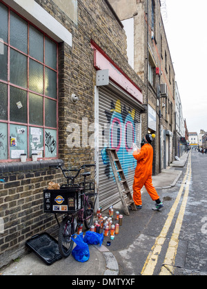 Streetart-Künstler, Ronzo, bei der Arbeit. Künstlerin Sprühfarben, riesigen Graffiti Monster an einer Tür - Fashion Street, London, UK zu malen Stockfoto