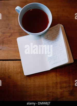 Eine kalte Tasse Kaffee und eine handschriftliche Zeitschrift. Stockfoto