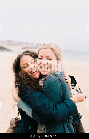 Zwei Frauen Wange an Wange umarmt am Strand. Stockfoto