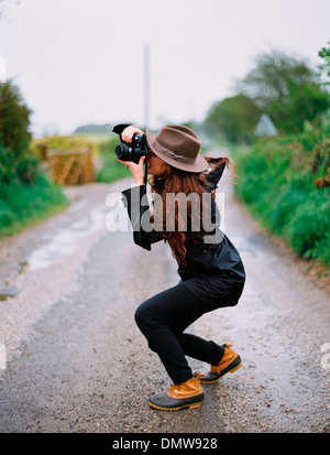 Eine Frau, um ein Foto auf einer Landstraße hocken. Stockfoto