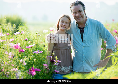 Im Sommer auf einem Bio-Bauernhof. Ein Mann und ein Mädchen in einem Feld von Blumen. Stockfoto