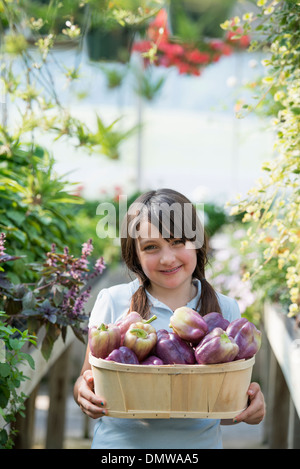 Im Sommer auf einem Bio-Bauernhof. Ein Mädchen hält einen Korb mit frischen Paprika. Stockfoto