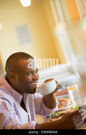 Ein Mann in einem Café hält eine Tasse Kaffee. Stockfoto