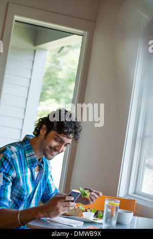 Ein Mann, sein Telefon an einem Cafétisch überprüfen. Stockfoto