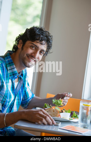 Ein Mann, sein Telefon an einem Cafétisch überprüfen. Stockfoto