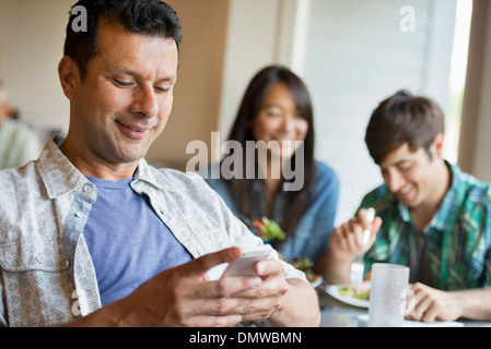 Drei Menschen an einem Cafétisch sitzen. Stockfoto