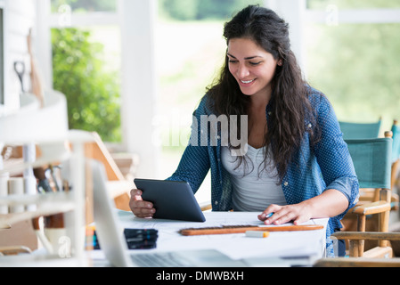 Eine Frau an einem Tisch mit einem digitalen Tablet arbeiten. Stockfoto