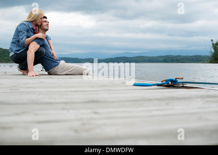 Ein Mann und eine Frau sitzend auf einem Steg am See. Stockfoto