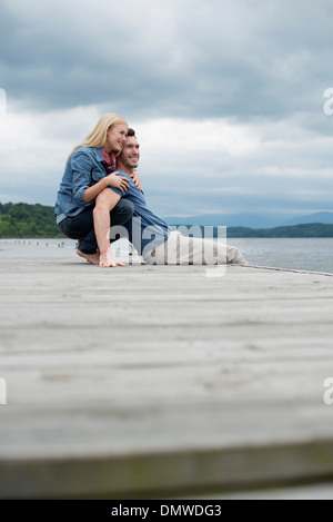 Ein Mann und eine Frau sitzend auf einem Steg am See. Stockfoto