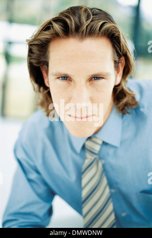 Ein junger Mann mit lockigen braunen Haaren trug ein blaues Hemd und Krawatte. Stockfoto