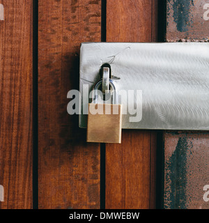 Nahaufnahme von einer hölzernen Tür mit einem Vorhängeschloss. Stockfoto