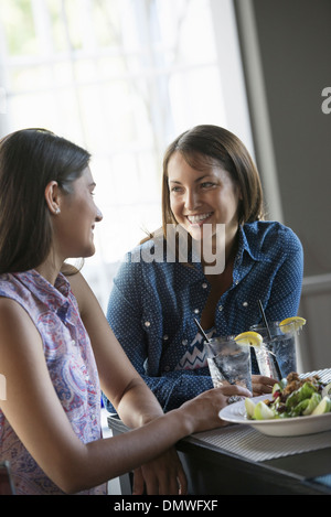 Zwei Frauen sitzen an einem Cafétisch mit einer Mahlzeit. Stockfoto