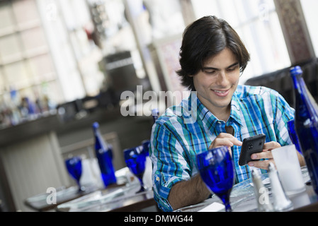 Ein Mann sitzt in einem Café mit einem Smartphone. Stockfoto