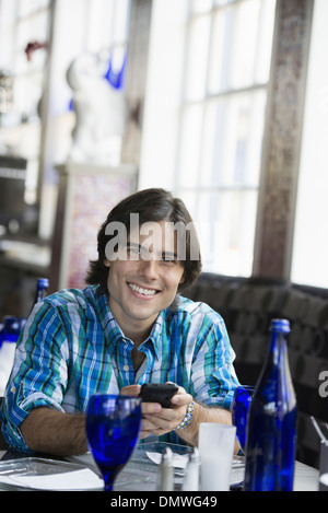 Ein Mann sitzt in einem Café mit einem Smartphone. Stockfoto