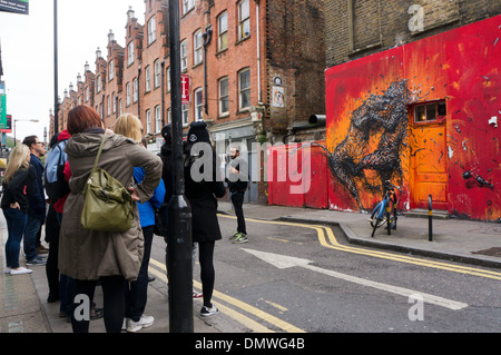 Ein Graffiti-Tour vor eine große Graffiti von zwei Kämpfe Großkatzen von DALeast in der Hanbury Street, in der Nähe von Brick Lane, Whitechapel Stockfoto