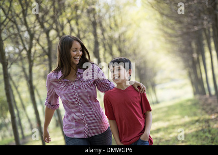 Eine Frau und ein Kind zu Fuß hinunter eine Allee von Bäumen. Stockfoto