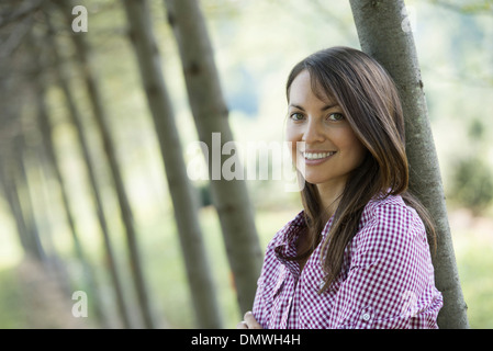 Eine Frau in eine Allee von Bäumen Lächeln auf den Lippen. Stockfoto