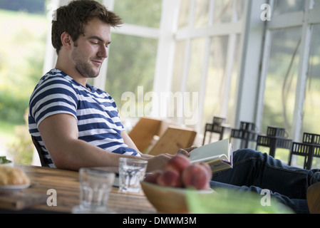 Ein Mann sitzt an einem Tisch, ein Buch zu lesen. Stockfoto