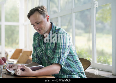 Ein Mann sitzt an einem Tisch, ein Buch zu lesen. Stockfoto