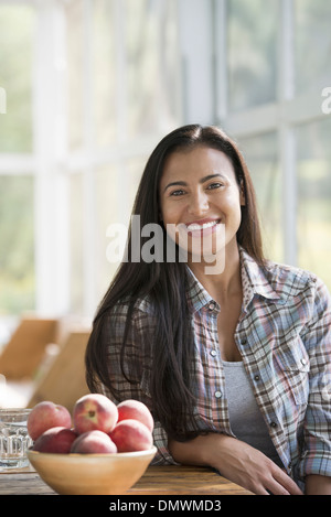 Eine glückliche junge Frau sitzt an einem Tisch. Stockfoto